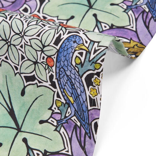 Detail of tea towel with a pattern of foliage, birds and strawberries.